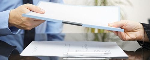 A person holding papers and pen in front of a window.